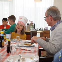 Kinderen eten pannenkoek met ouderen