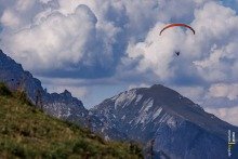 Paragliders Above Stubai Valley Against Cloudy Blue Sky